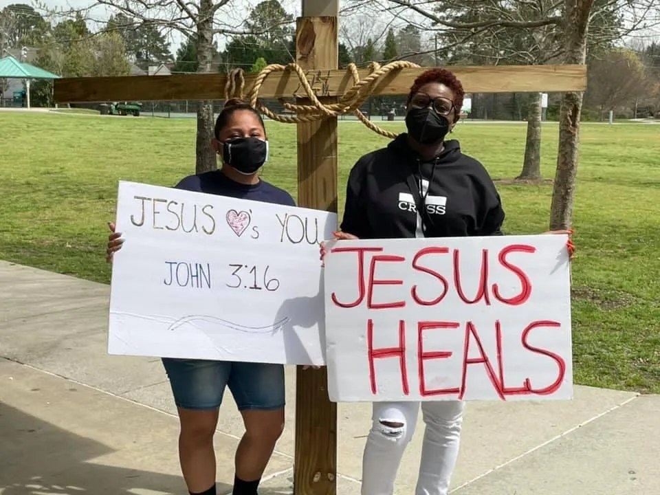 Two women holding signs that read Jesus heals